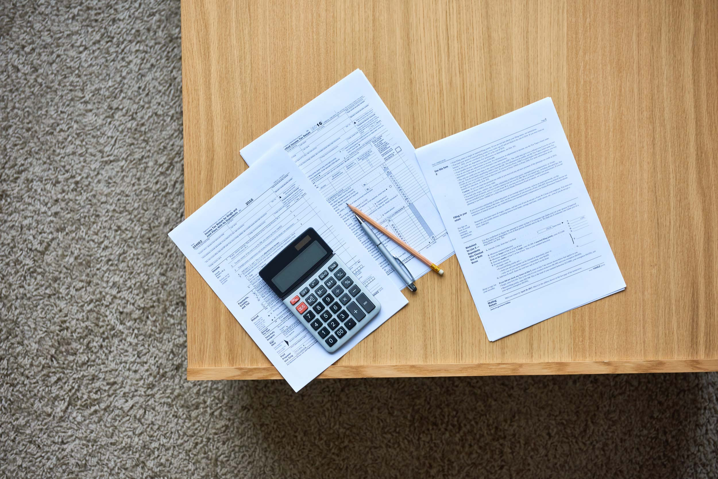 tax forms 1040, pencil and pen with calculator on desk