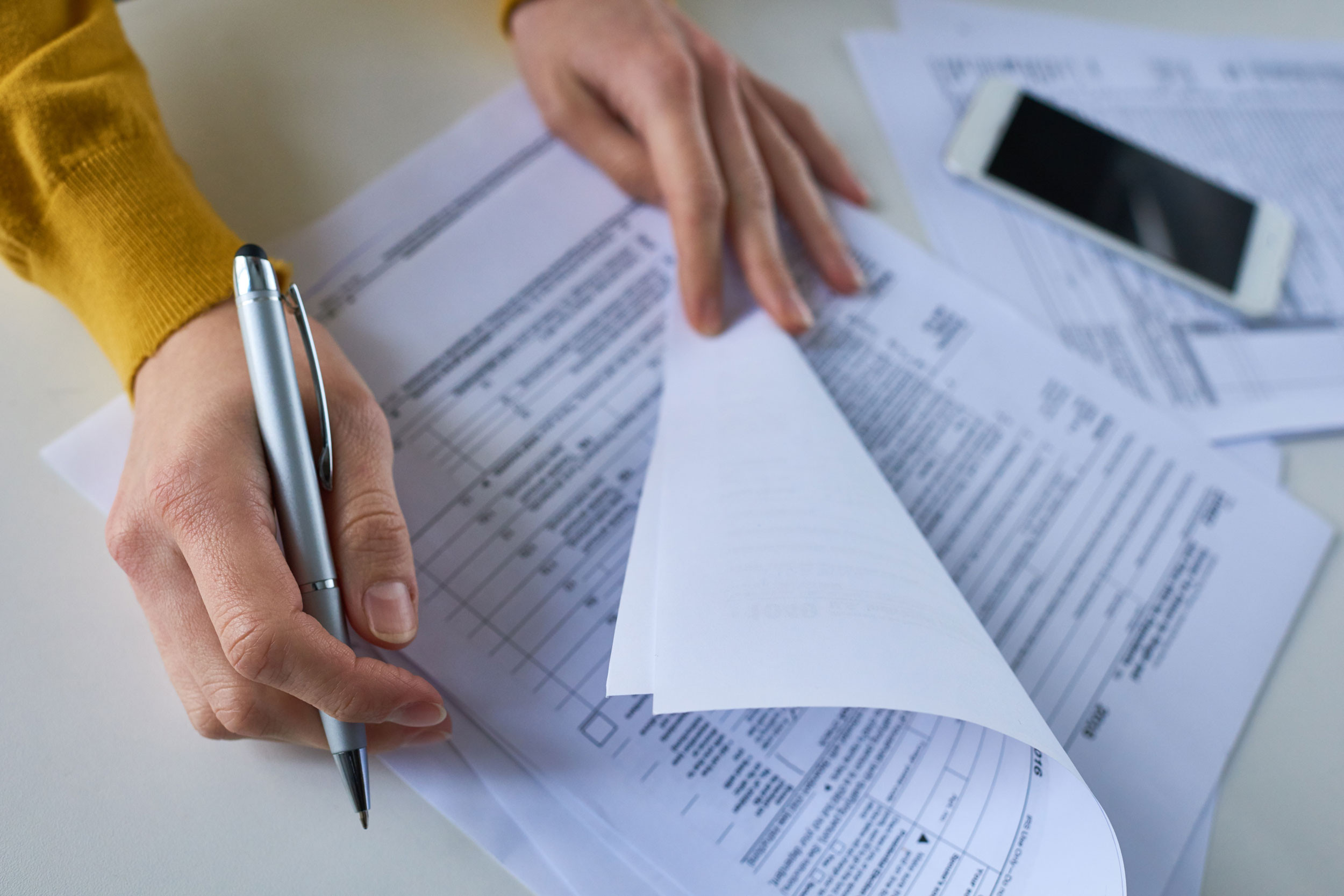 person hand holding pen with income tax return forms