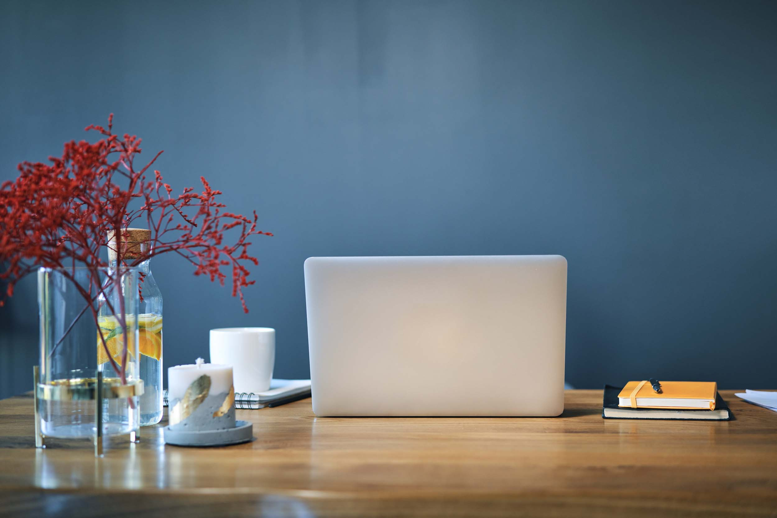 workplace with laptop, plant, notebook, pen and candle on table