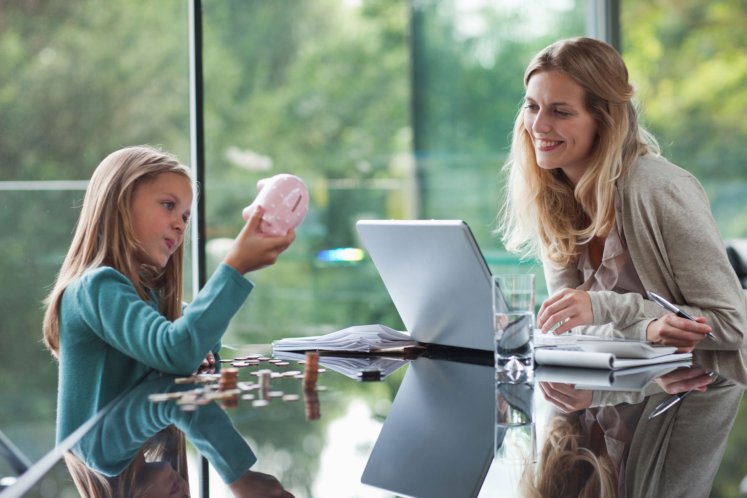 mother and daughter discussing about tax planning with laptop and piggybank