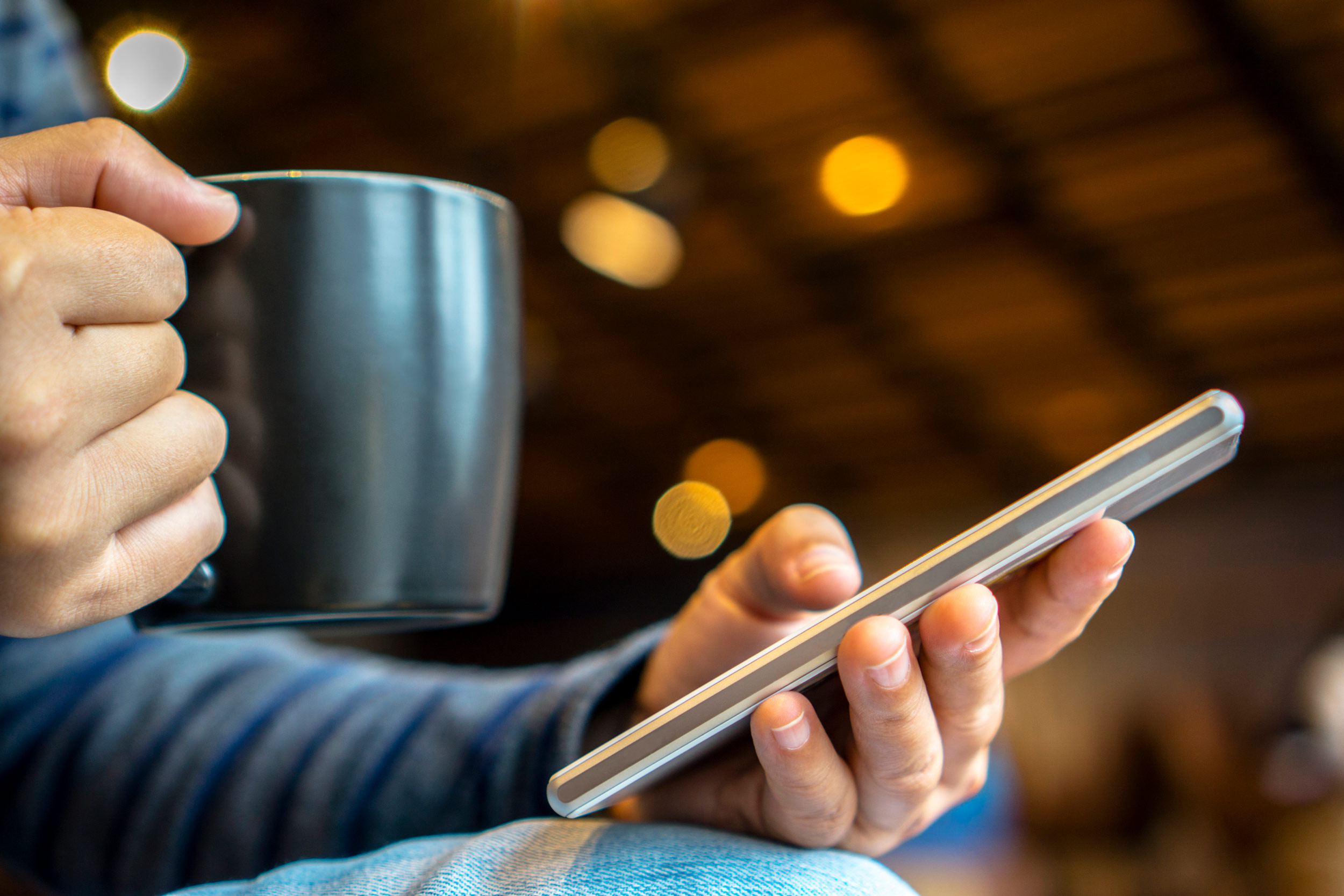 person using mobile device with coffee