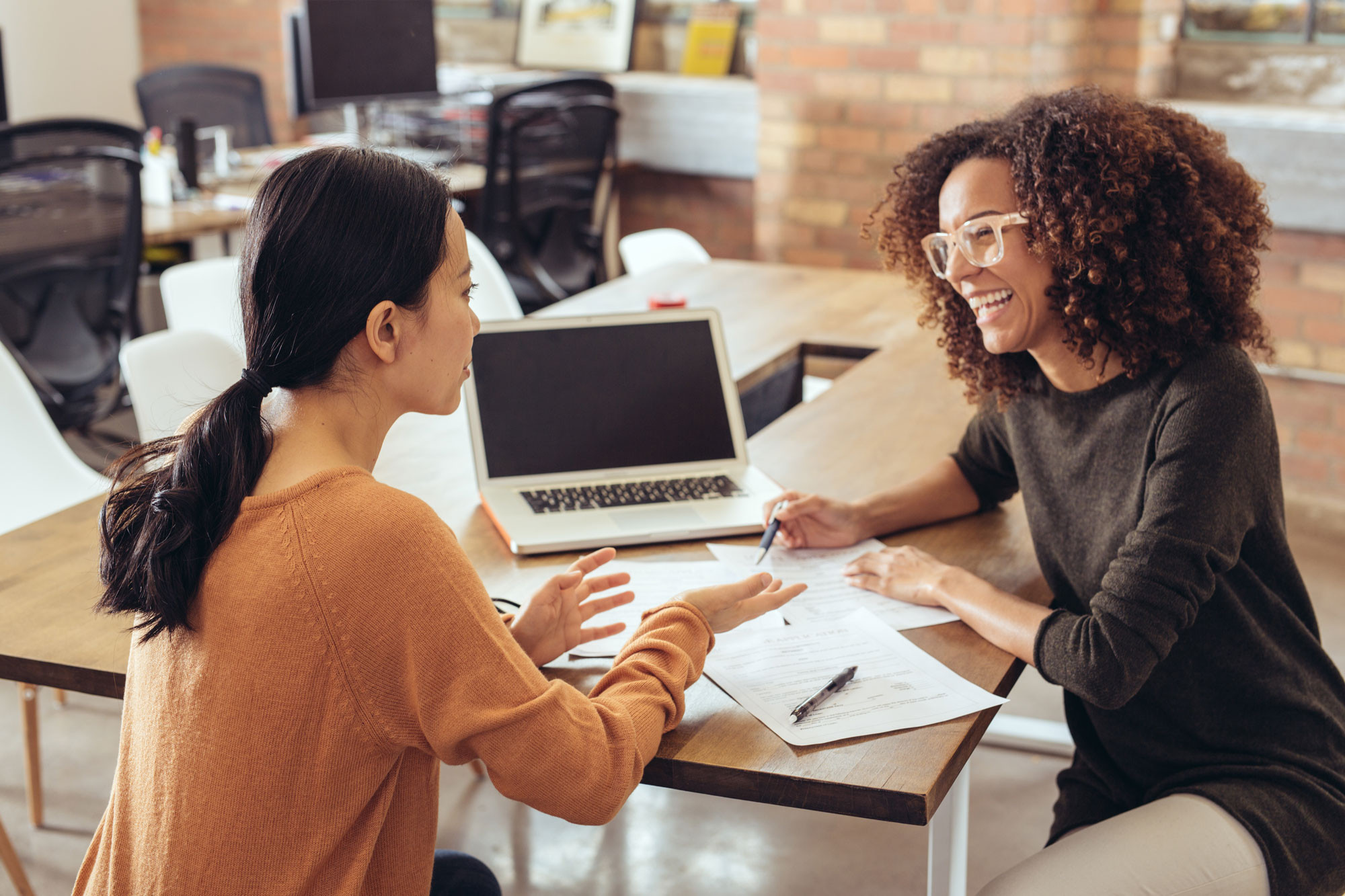 diverse coworkers sitting and laughing with laptop