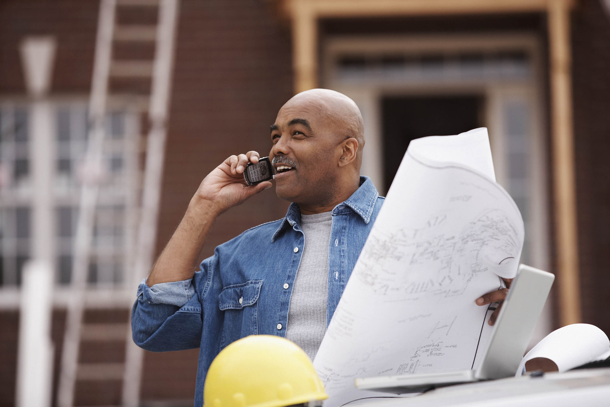 blueprint in hand talking on phone with contractor