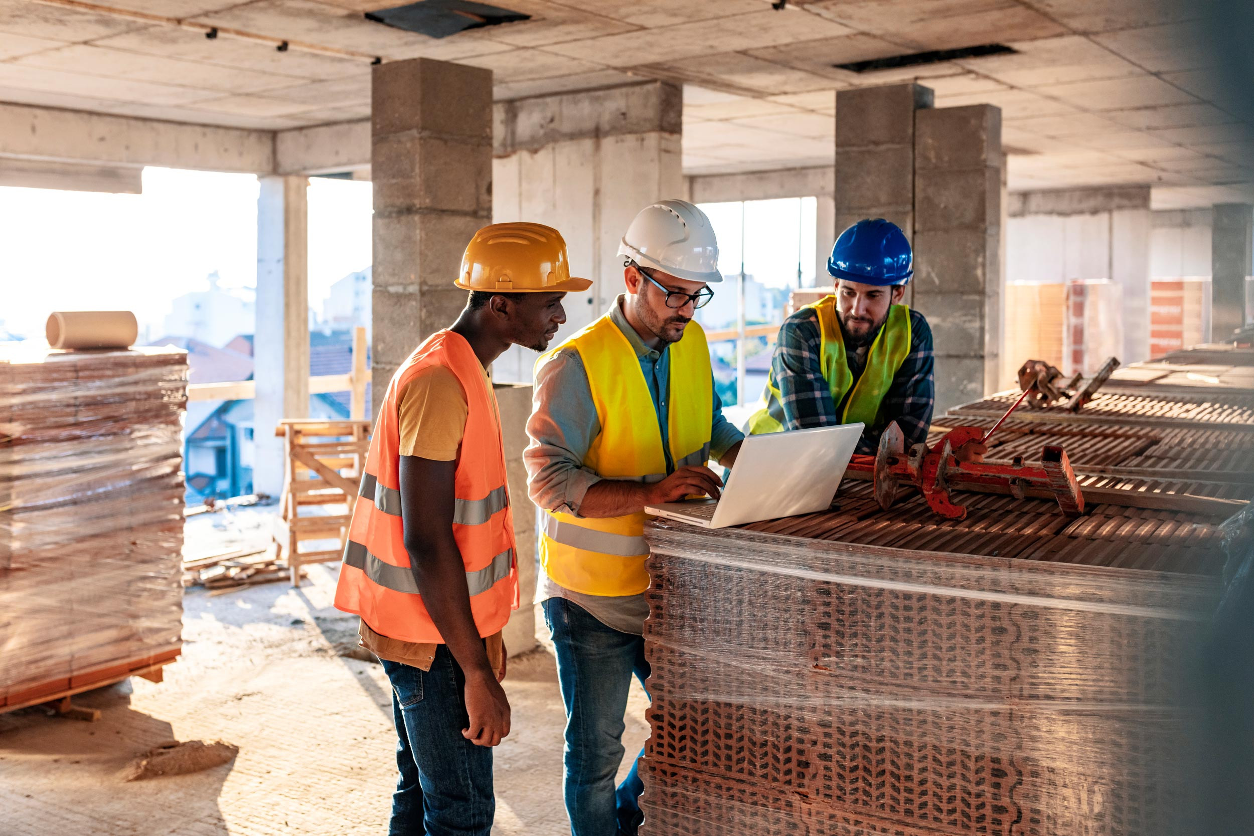 people in hardhats with computer on construction site