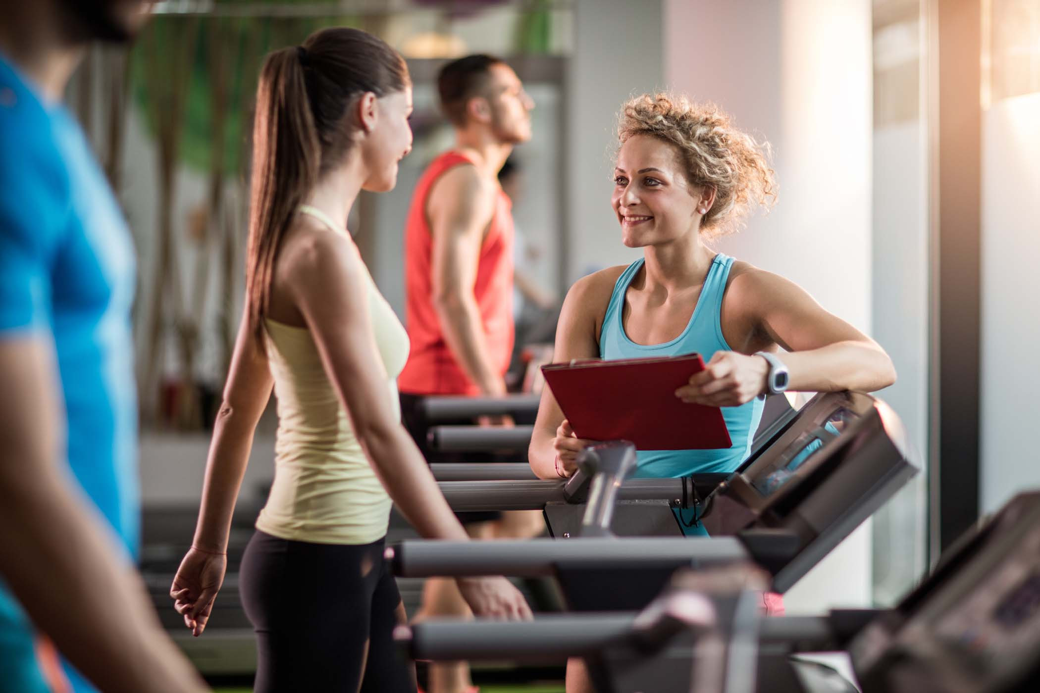 smiling personal coach talking person in a gym