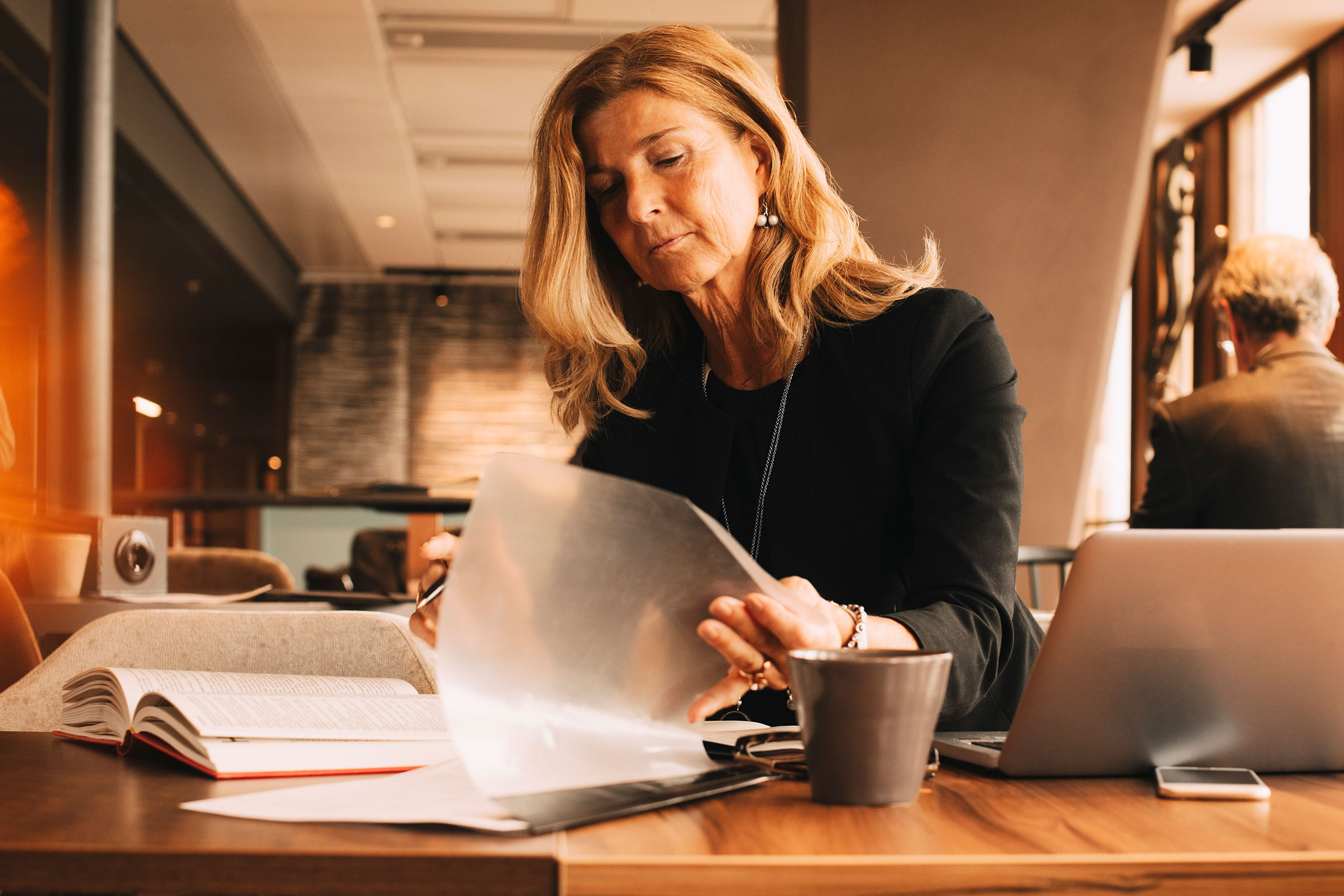 A professional woman reviews financial documents at a desk.