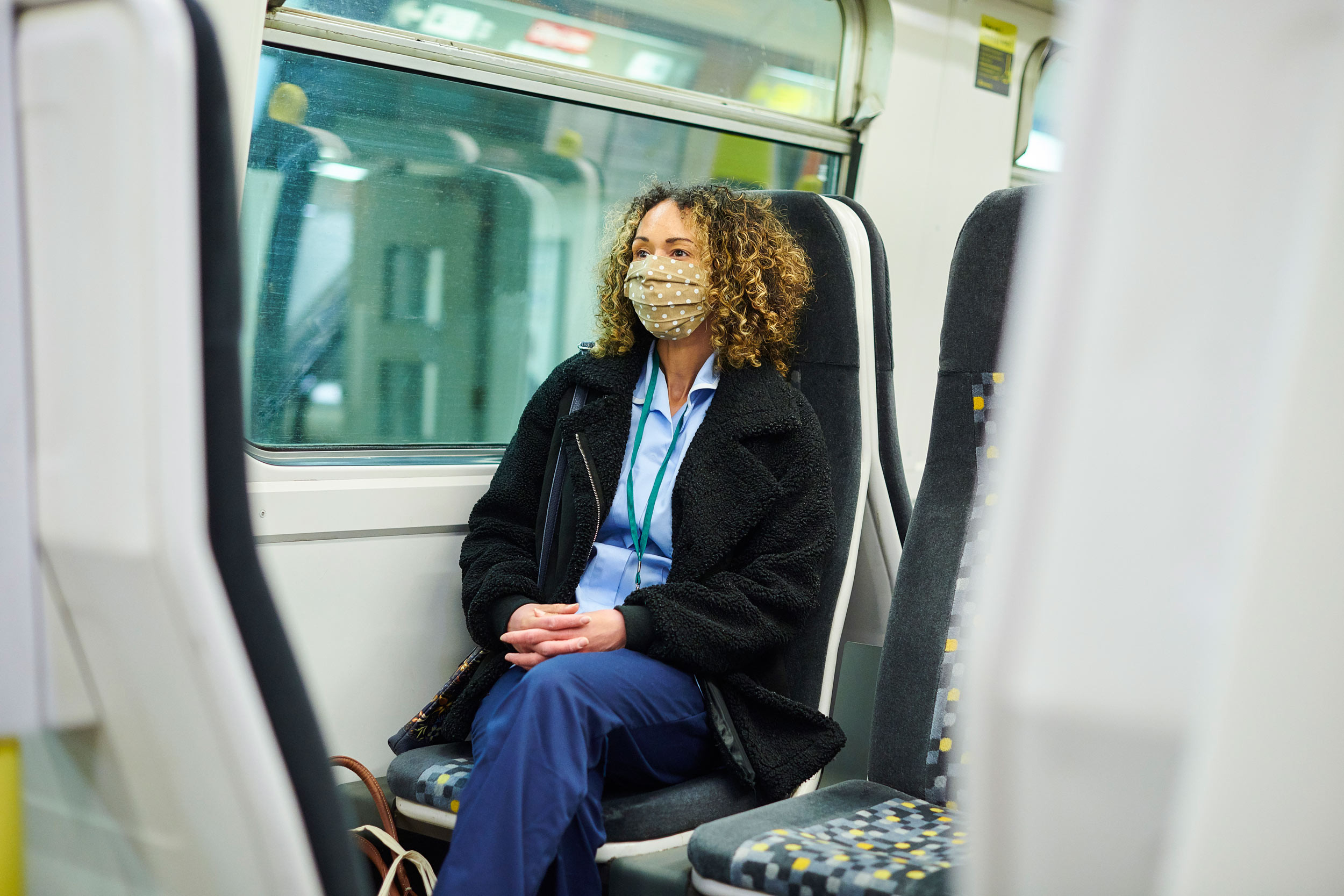 travel nurse wearing medical mask relaxing in train seat