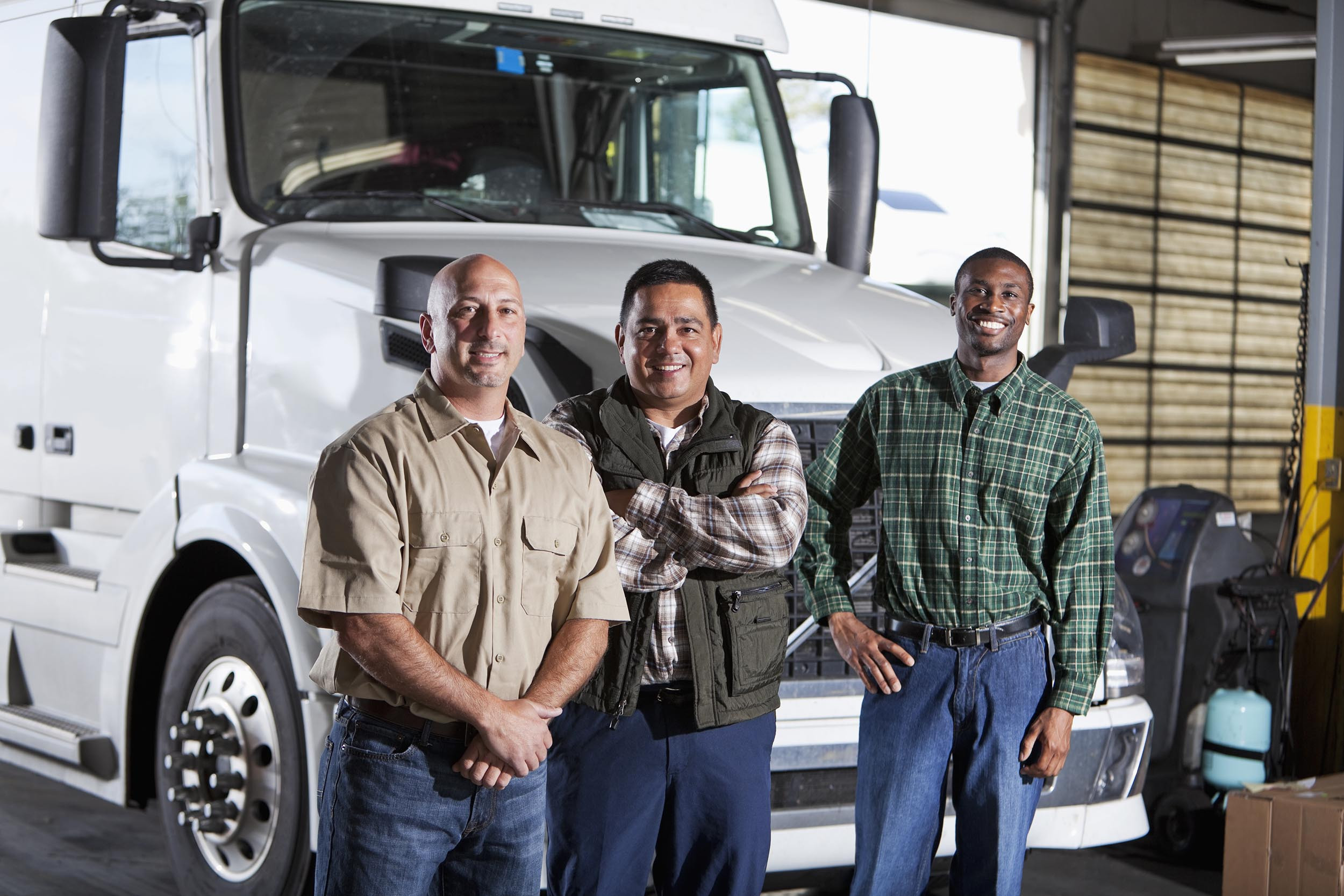 multi-ethnic people standing next to semi-truck