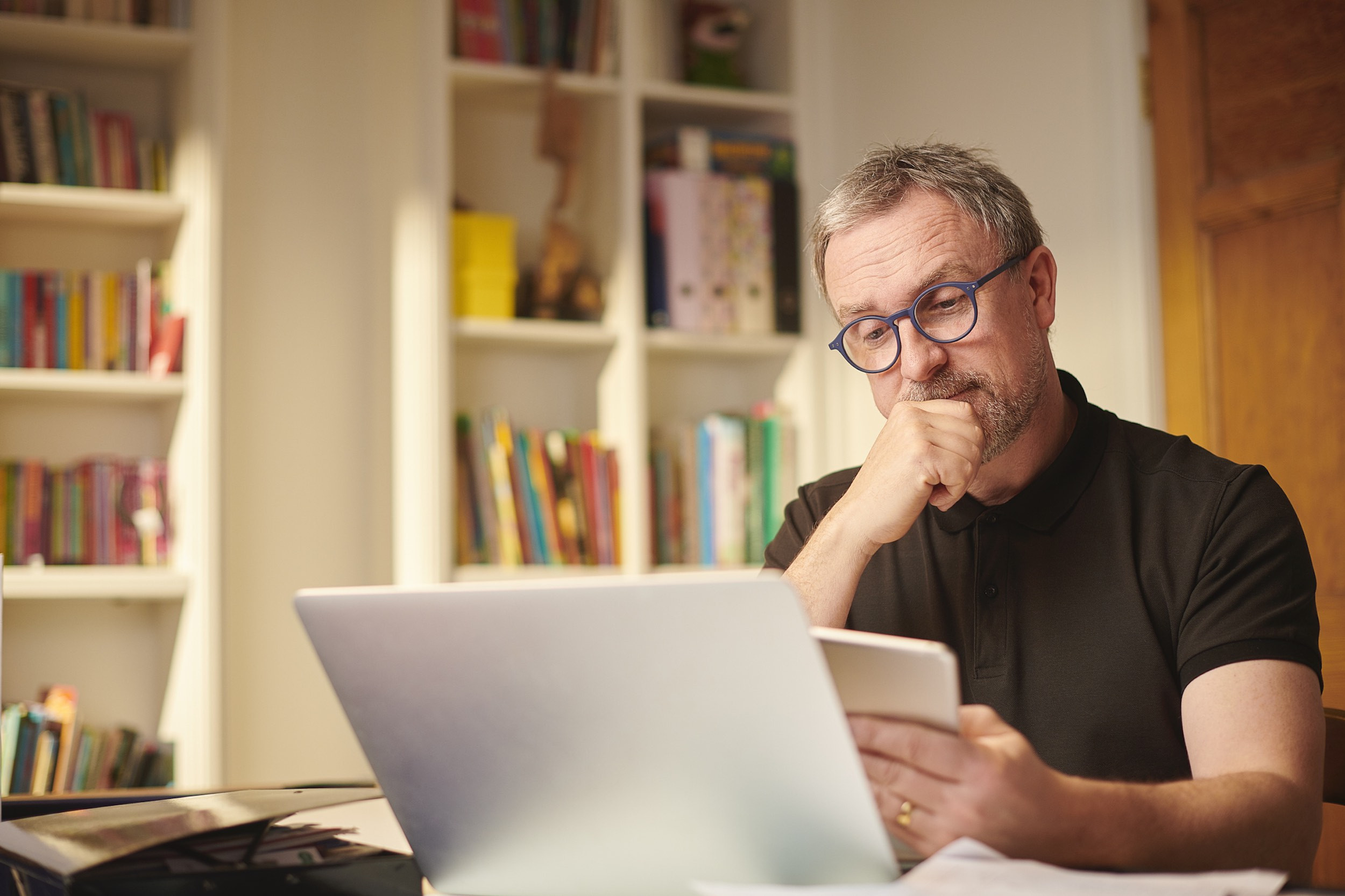 business person thinking with laptop behind the bookshelves