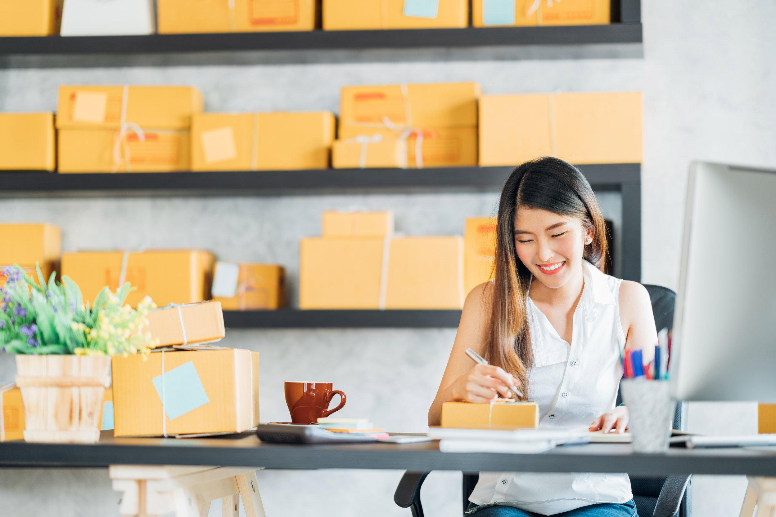 small business owner working at home office with shipping details on box