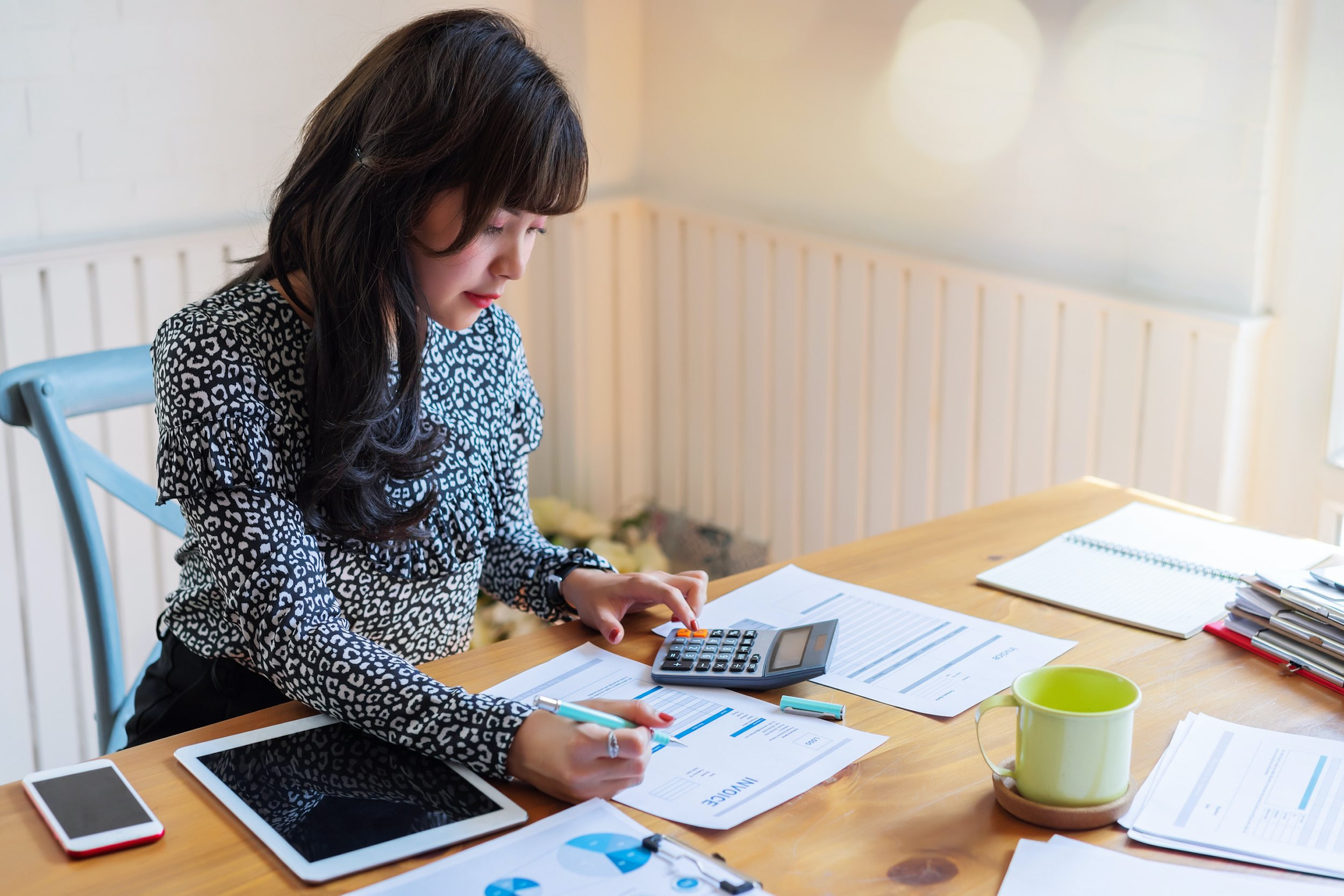 business person working at desk with calculator and invoice documents