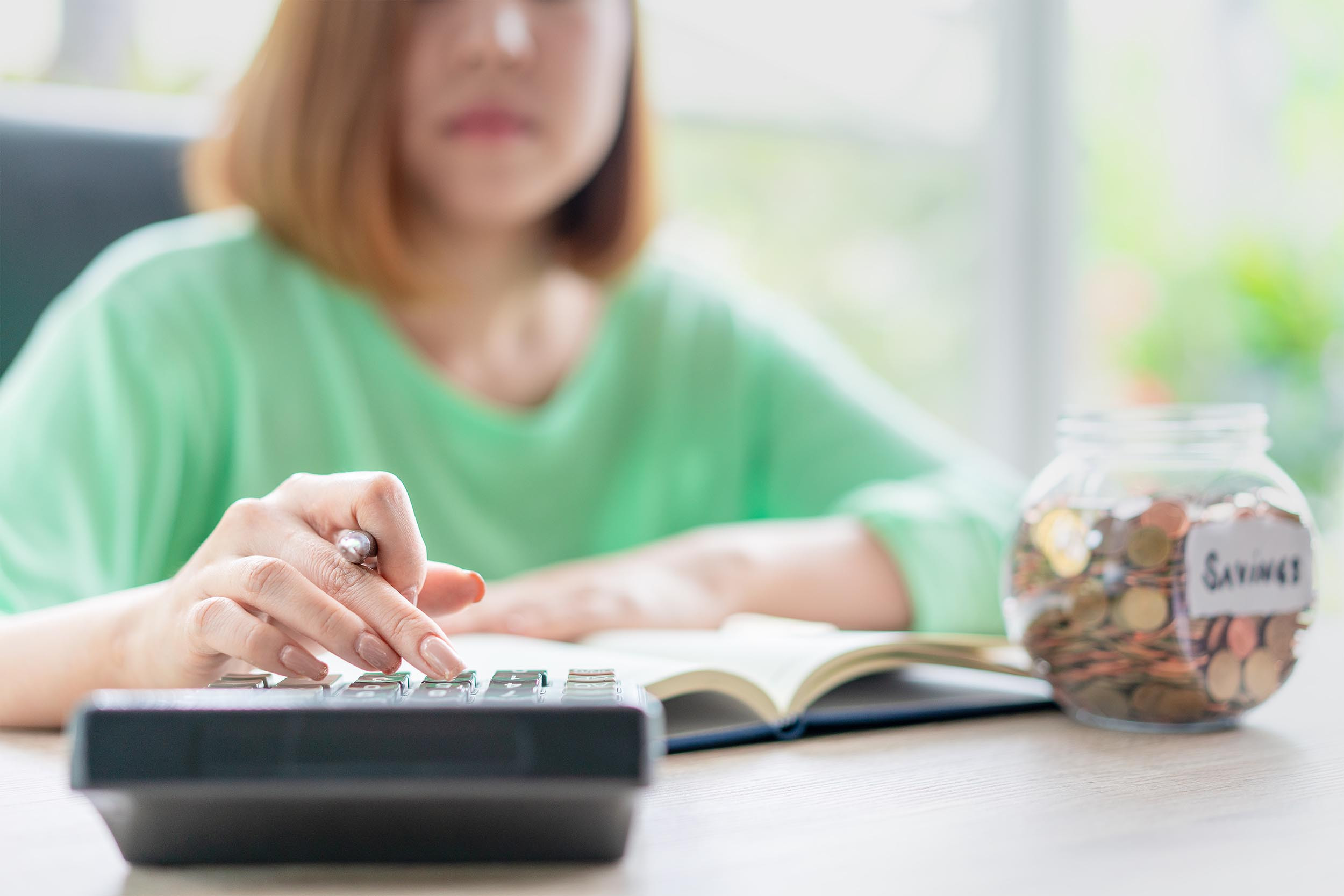 a person calculating savings amount using calculator
