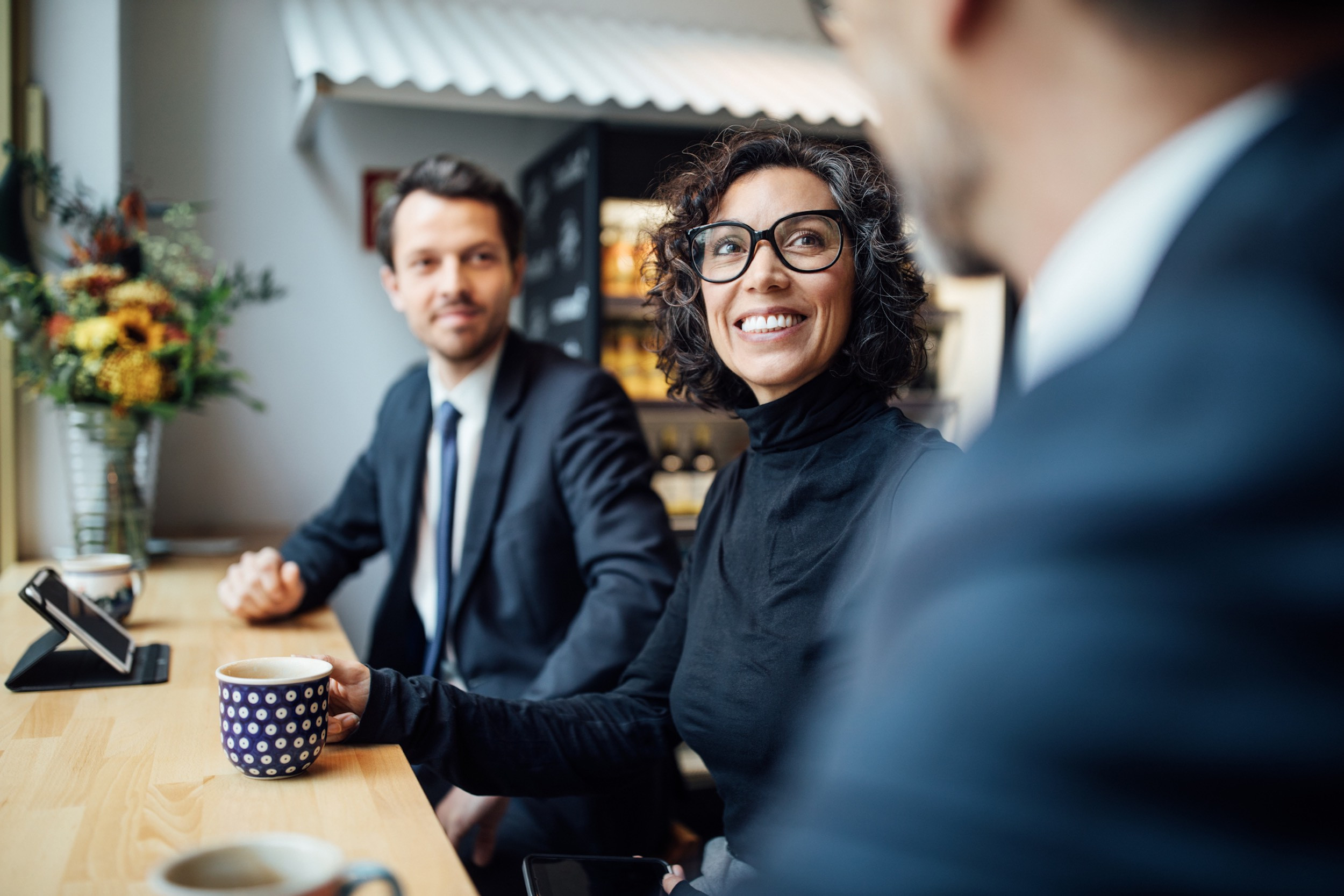 smiling three business people sitting at coffee shop