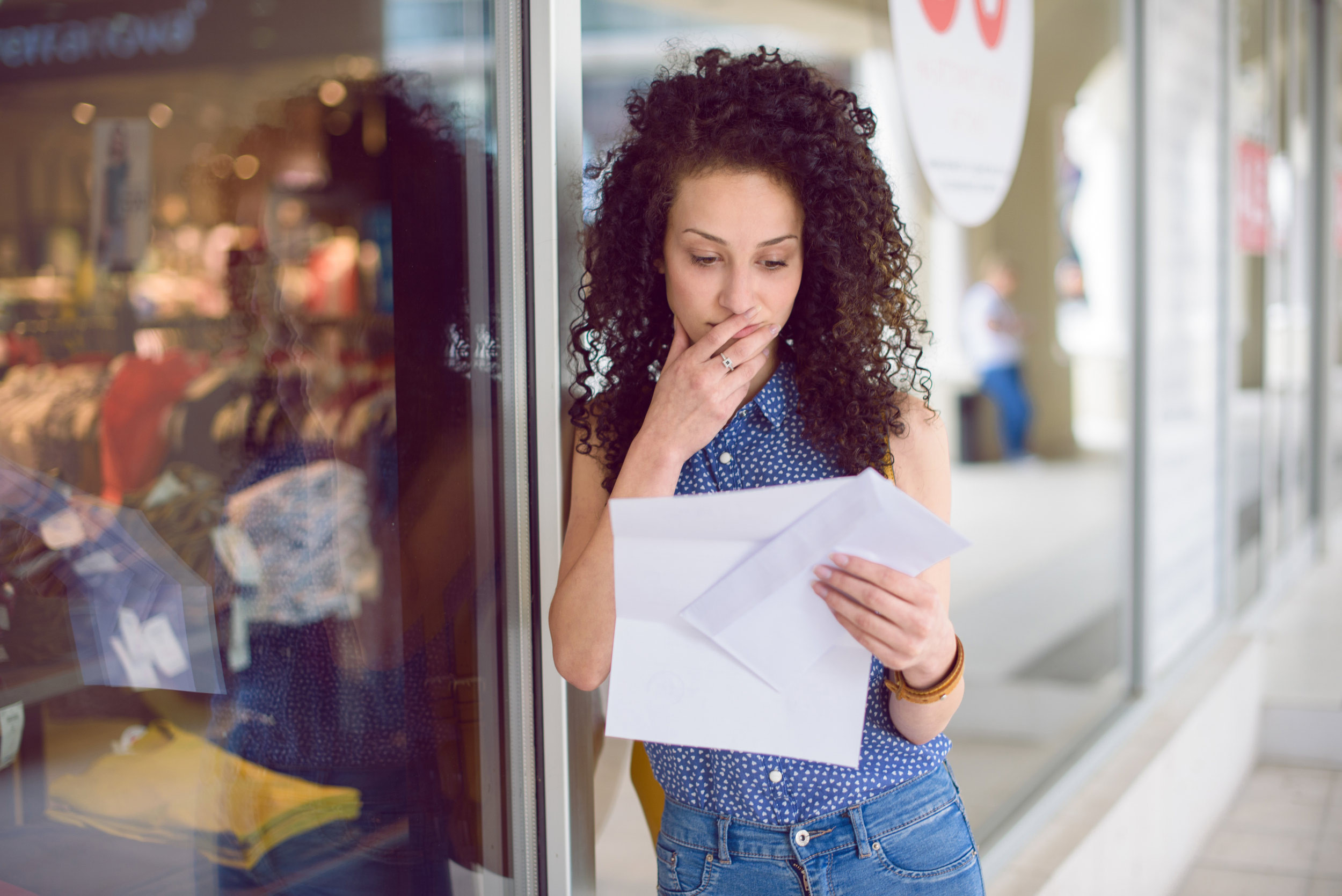 person reading letter at front of shop