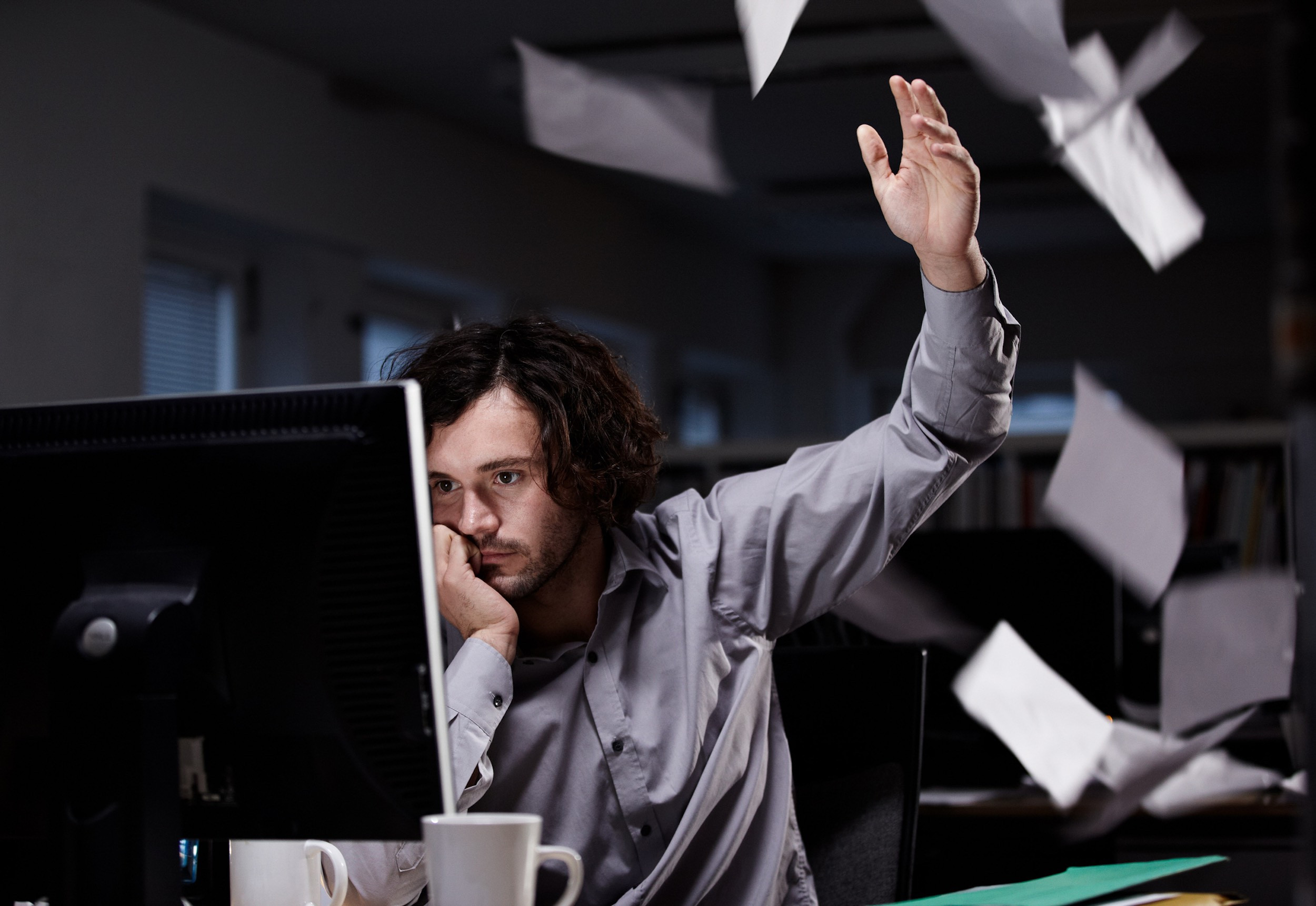 a person working from office and throughing papers on frustration