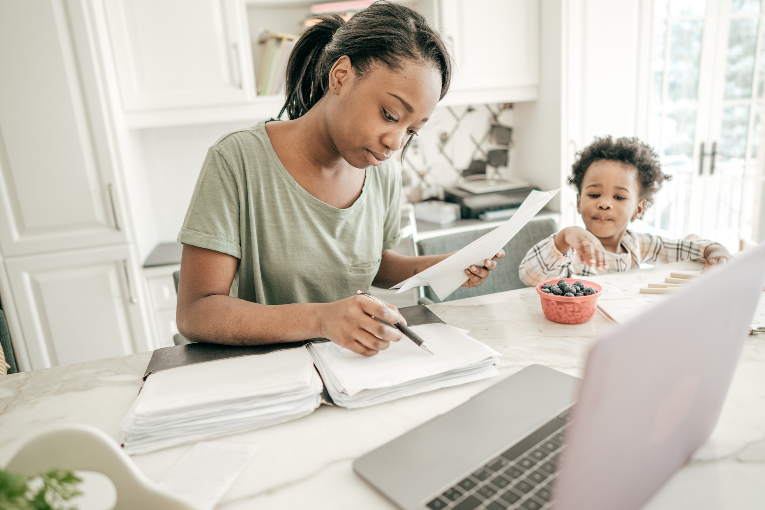 mother doing tax calculation with child in the kitchen