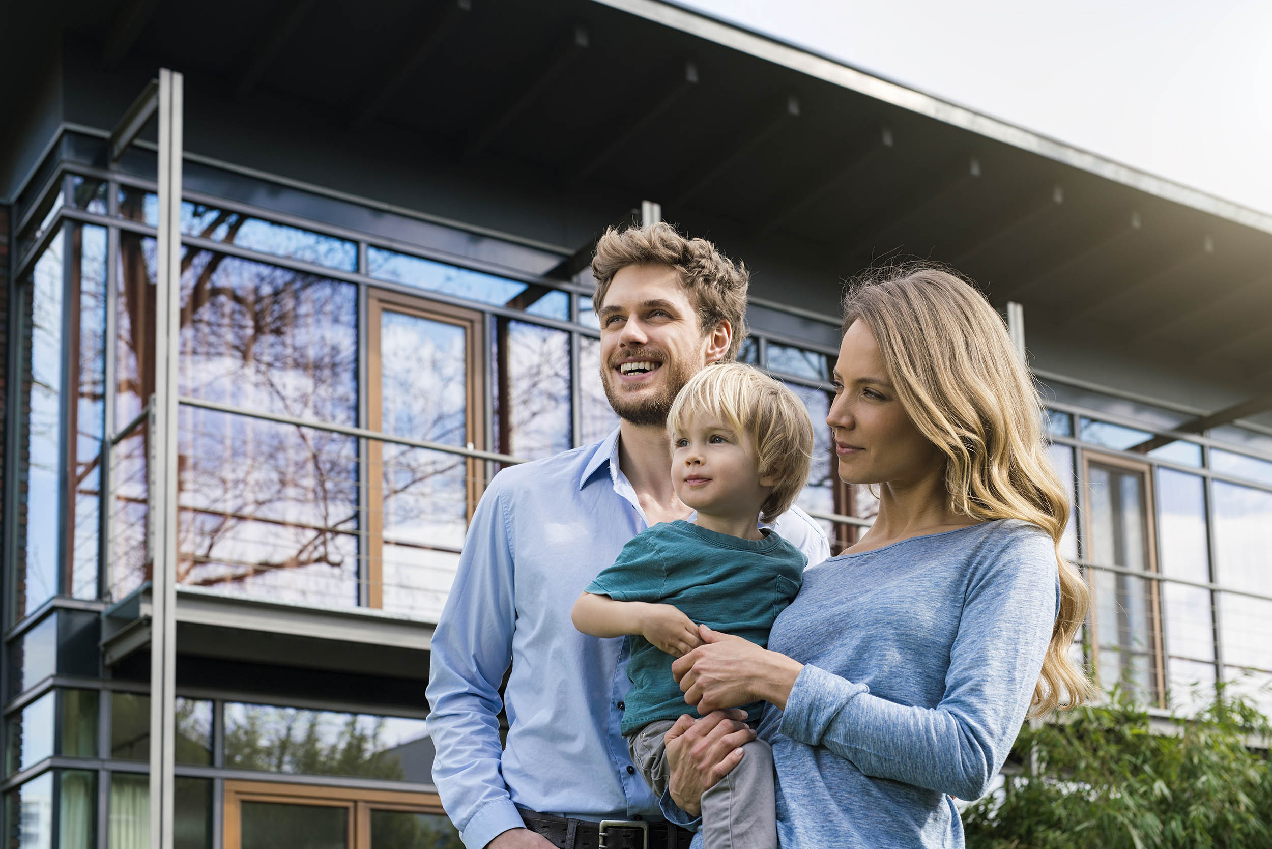 Upper-class couple with their child standing in front of a beautiful estate