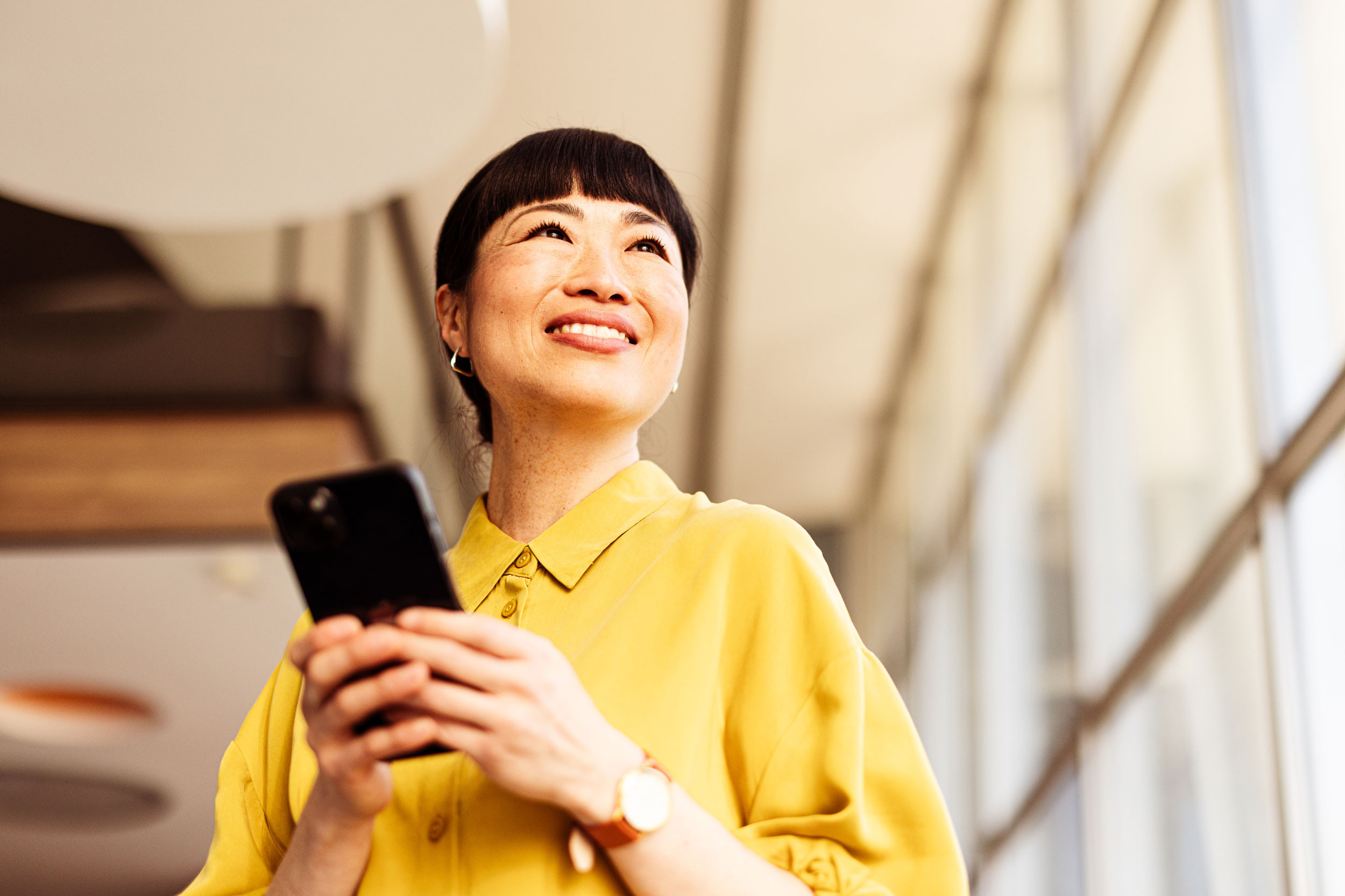 a smiling business person in an office holding their phone