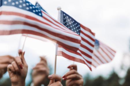hands waving US flags in the sky