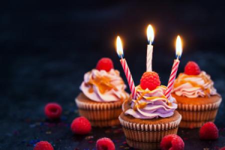 colorful raspberry cupcakes and candles in the dark