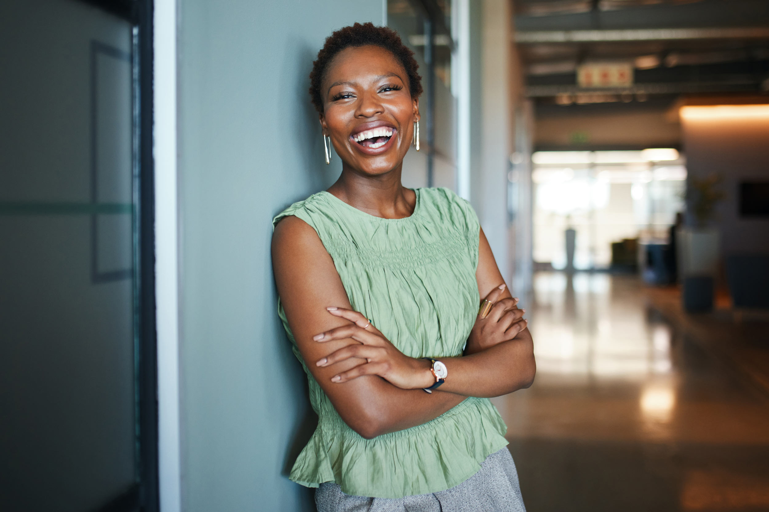 laughing businessperson leaning on office wall