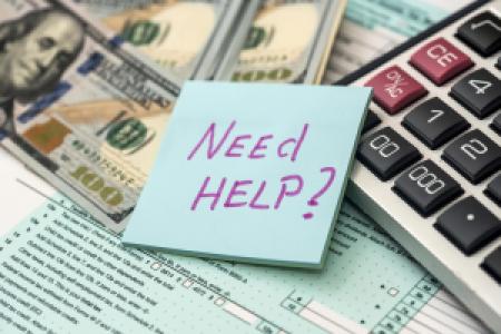 a Need Help sticky note, tax forms, money and calculator