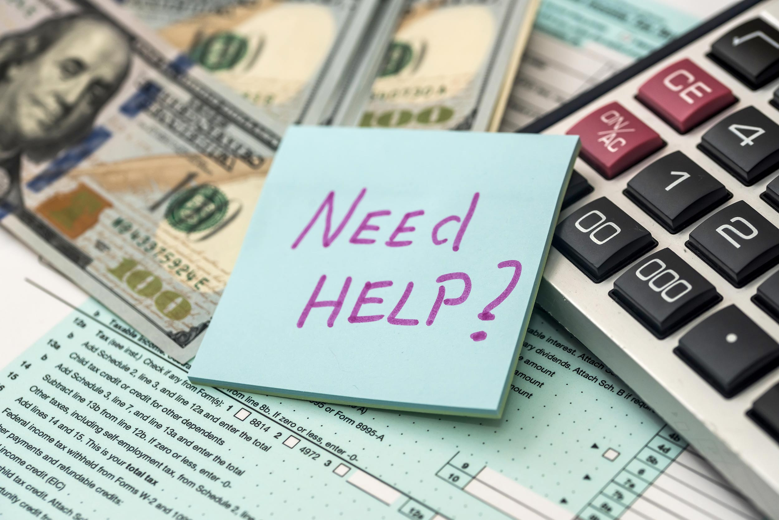 a Need Help sticky note, tax forms, money and calculator