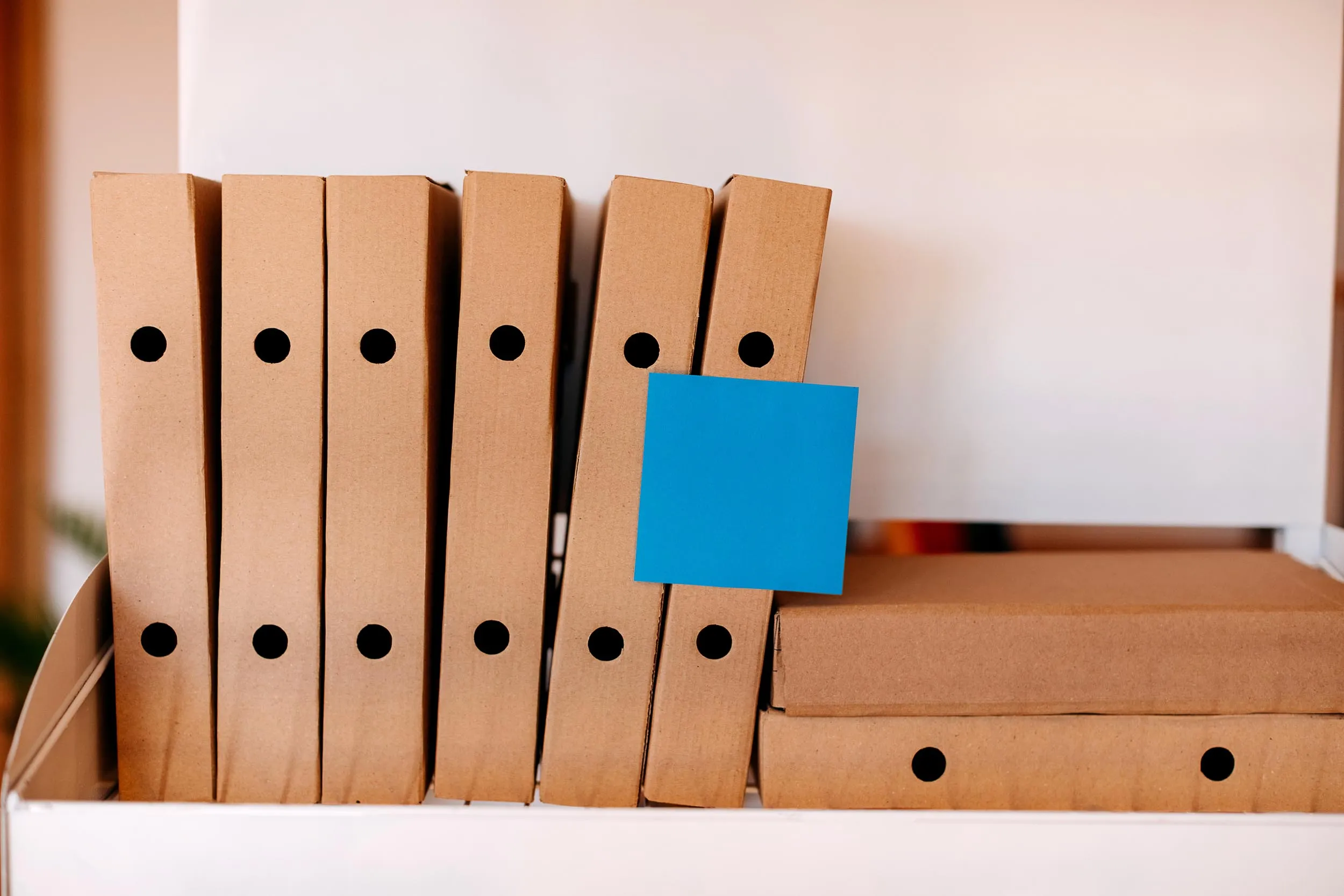 a row of brown folders and a blue sticky note