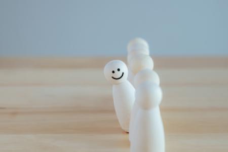 a smiling figure standing out among a queue