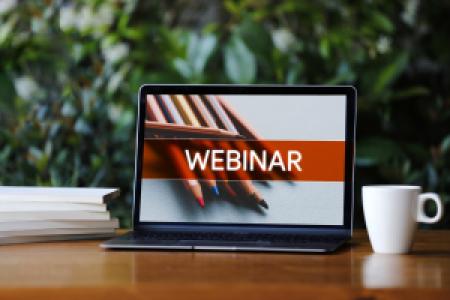 a laptop with webinar screen on wooden desk
