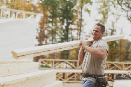 a construction worker carrying wooden beams
