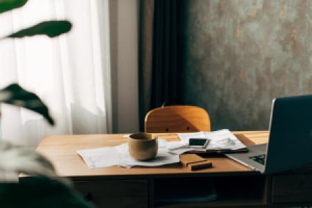 a quiet office desk with documents, a laptop and coffee