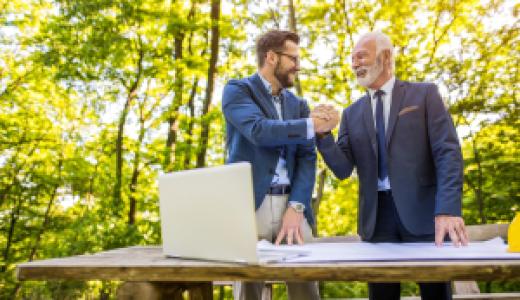 two businessmen shake hands at outdoor meeting